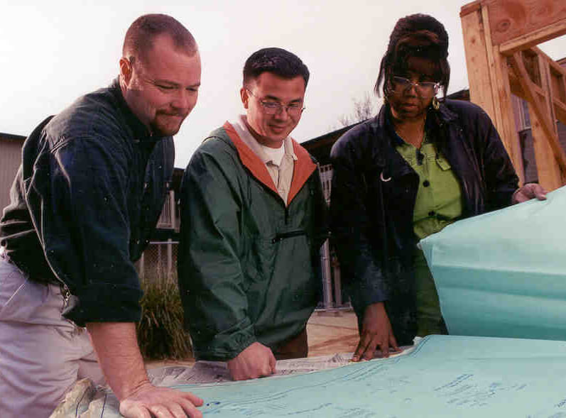 Two men and a female looking at a blueprint.