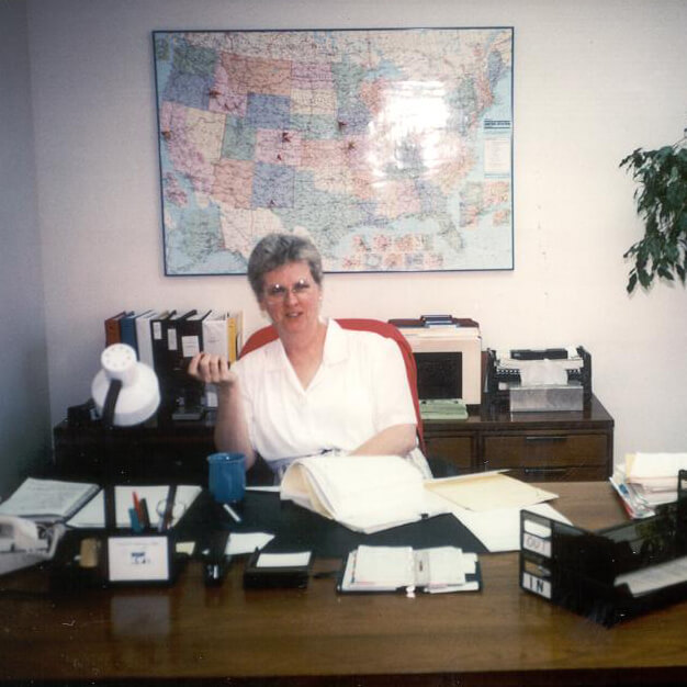 Sister Lillian Murphy sitting at desk, smiling towards camera.