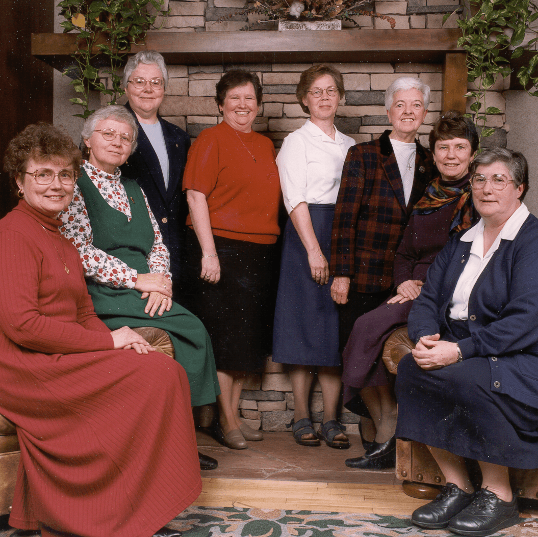A photo of a group of Sisters that are sponsors are sitting in a living room, all looking and smiling at the camera.