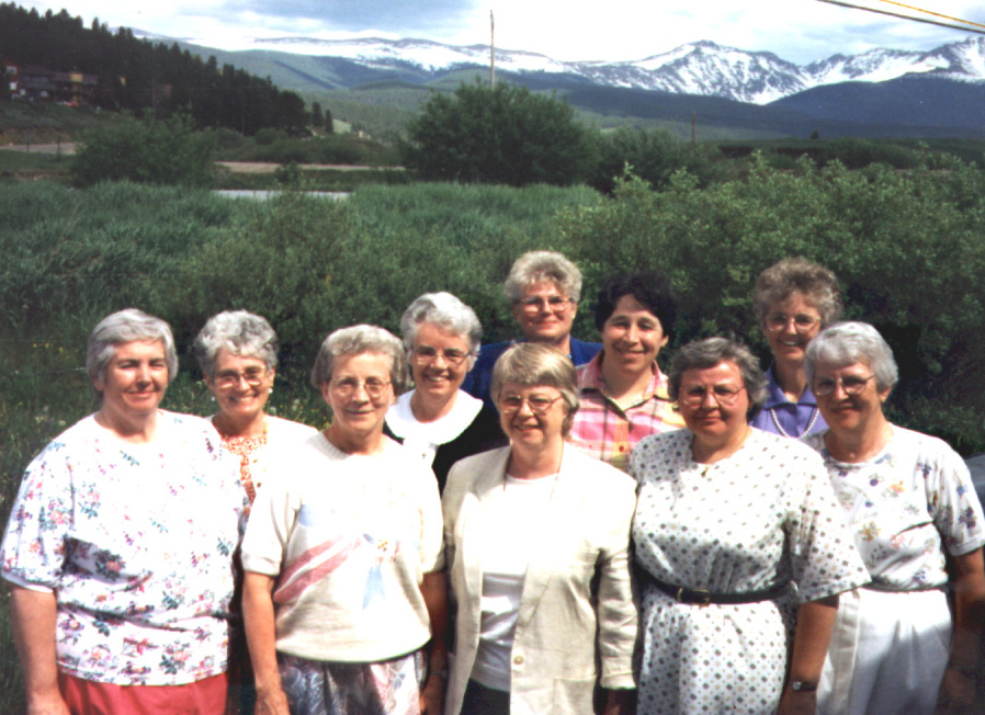 A group photo of many Sisters smiling towards the camera against a mountain backdrop.