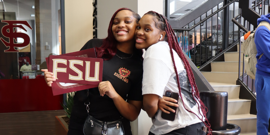College tour - two smiling college students with a sign