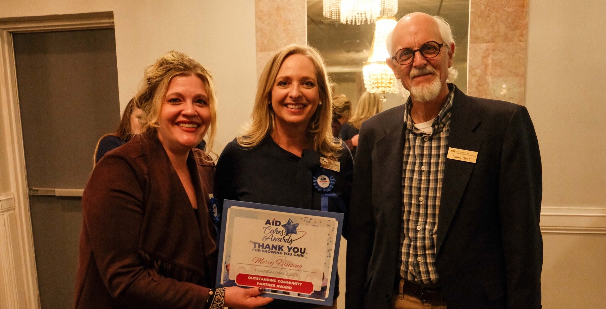 Three people post holding Mercy Housing's Cares Award